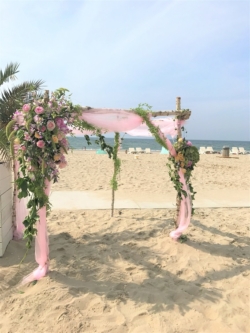 Dit prieel met grote bloemstukken geven een prachtige romantische look op het strand. Compleet verzorgd door Bruidsboeket & Zo & bloembinderij van der Maat
